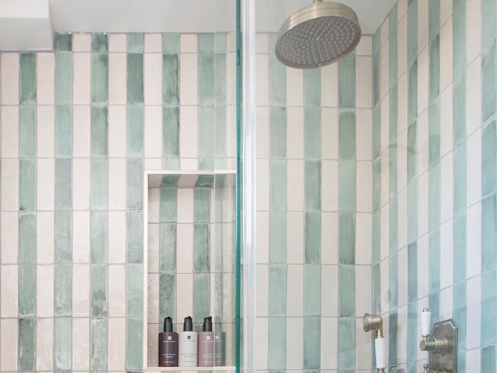 A bathroom with a shower and tiled walls at Apartment 1, 86 Dyer Street Cirencester