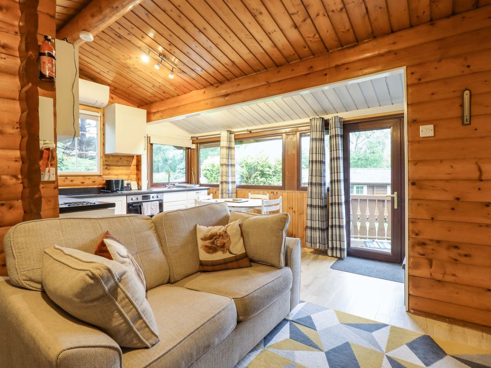 A living room with a sofa and kitchen view at Swn Yr Afon - No 333