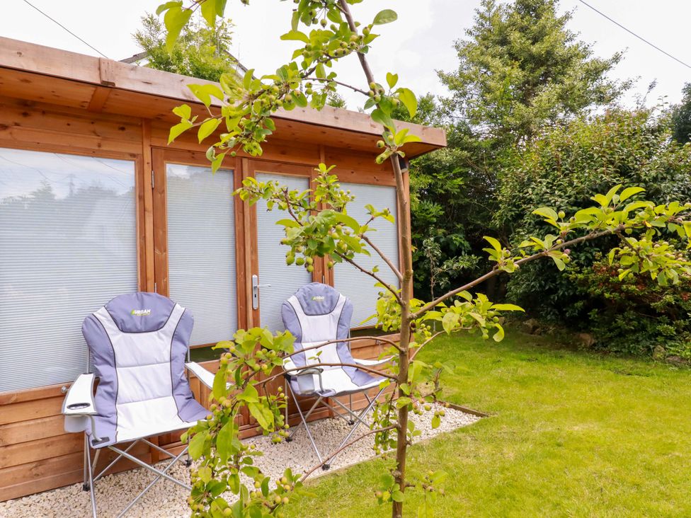 A garden with two folding chairs and a wooden structure at Heatherlea Cottage St. Austell
