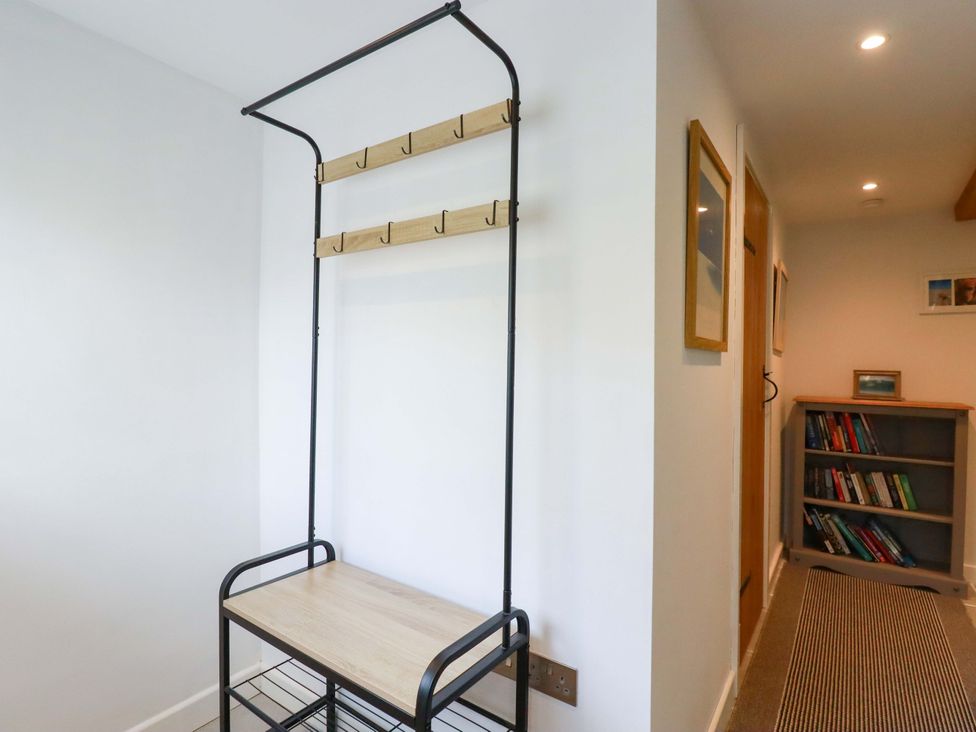 A coat rack with hooks and a shelf in the hallway at Heatherlea Cottage in St. Austell