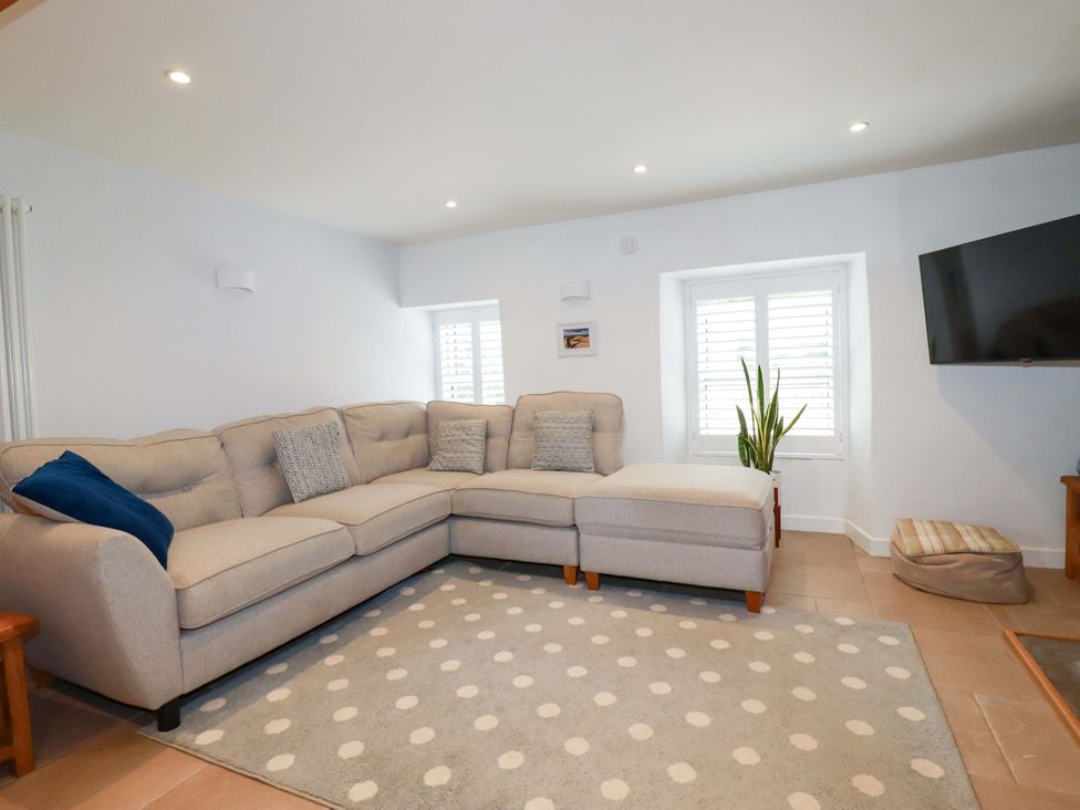 A living room with a sofa and television at Heatherlea Cottage, St. Austell