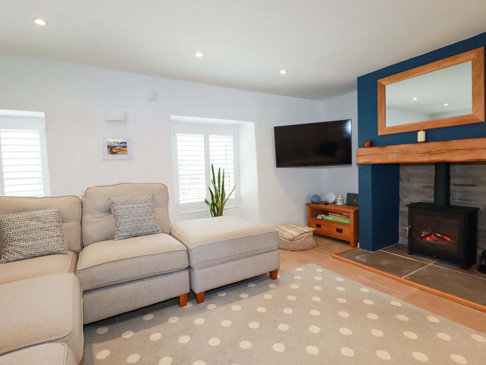 A living room with a sofa and television at Heatherlea Cottage in St. Austell