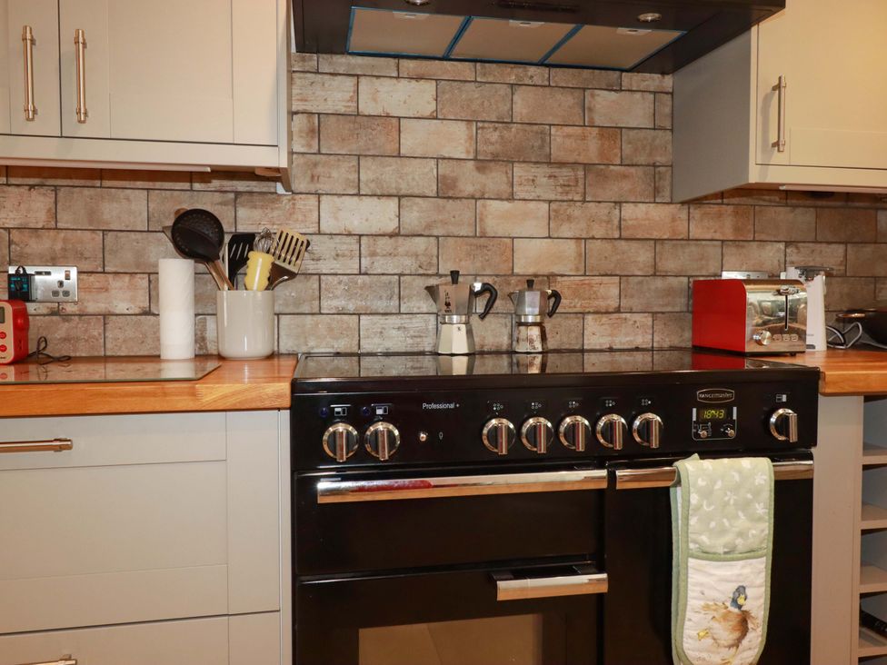 A kitchen with a stove and various appliances at Heatherlea Cottage in St. Austell