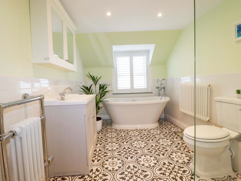 A bathroom with a bathtub and wash basin at Heatherlea Cottage St. Austell