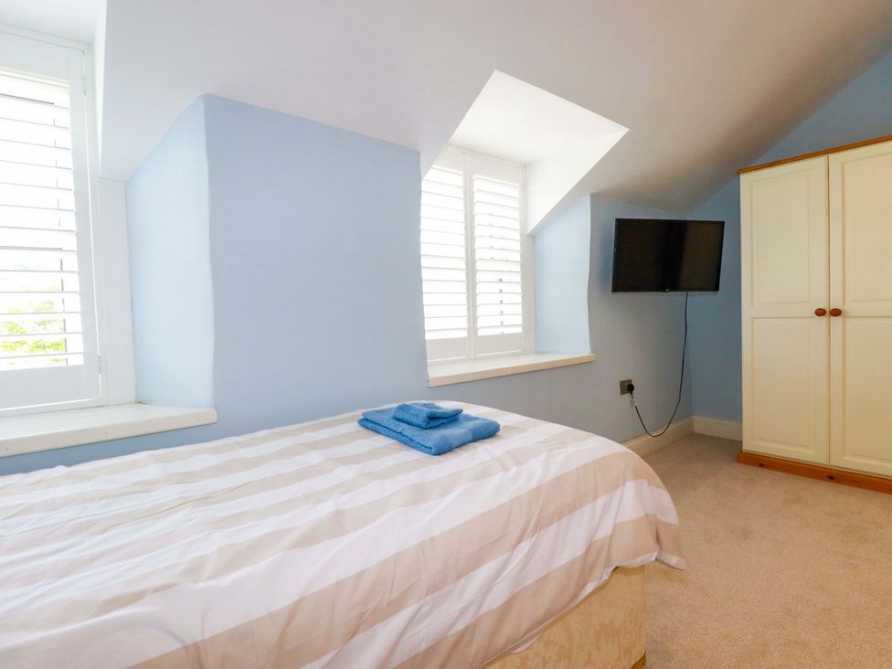 A bedroom with a bed and television at Heatherlea Cottage St. Austell