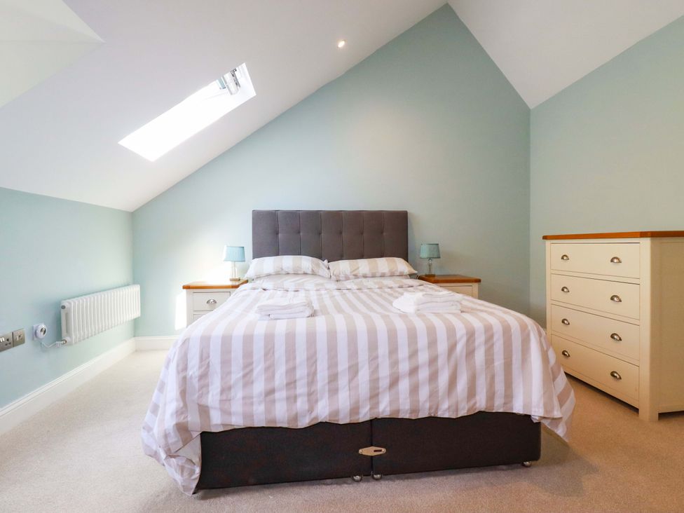 A bedroom with a bed and dresser at Heatherlea Cottage in St. Austell