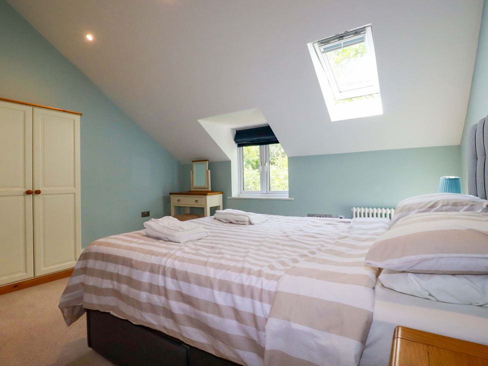 A bedroom with a bed and wardrobe at Heatherlea Cottage St. Austell