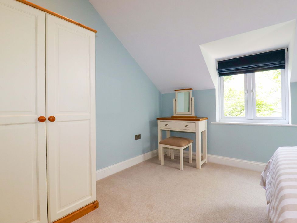A bedroom with a wardrobe and a vanity at Heatherlea Cottage St. Austell