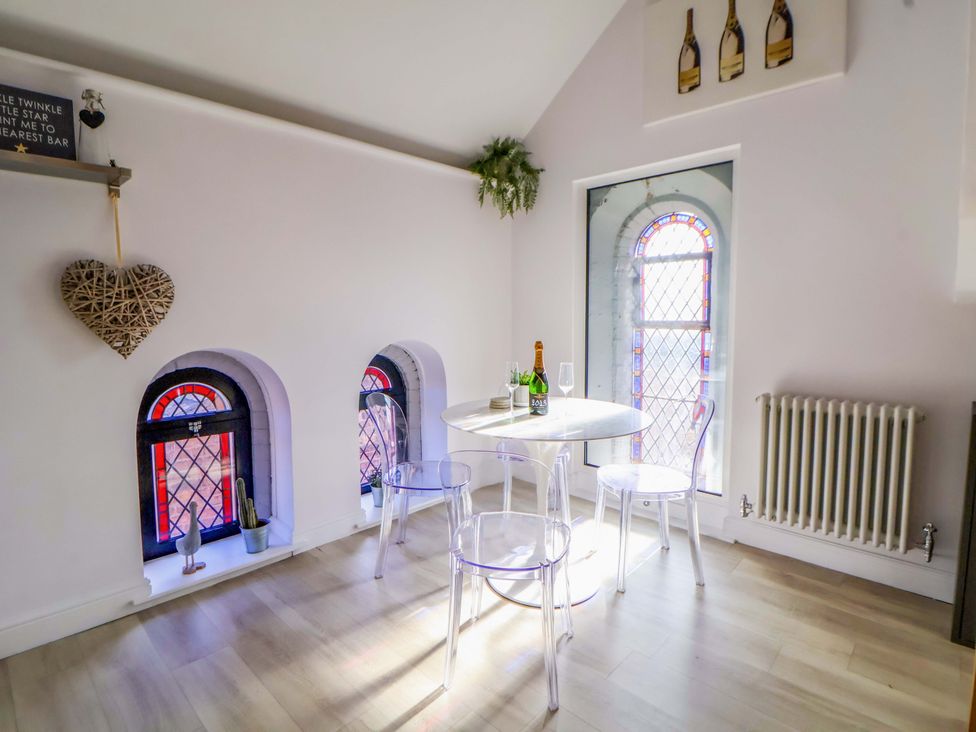 A dining area with a table and chairs and stained glass windows at 1 Chapel Place Chester