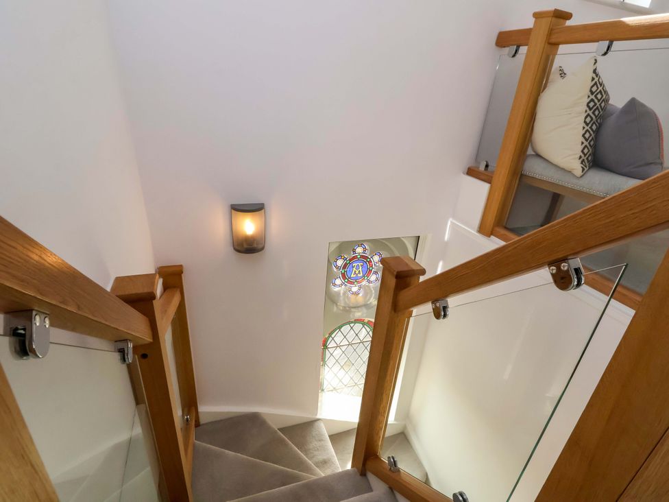 A stairwell with a stained glass window and light fixture at 1 Chapel Place in Chester