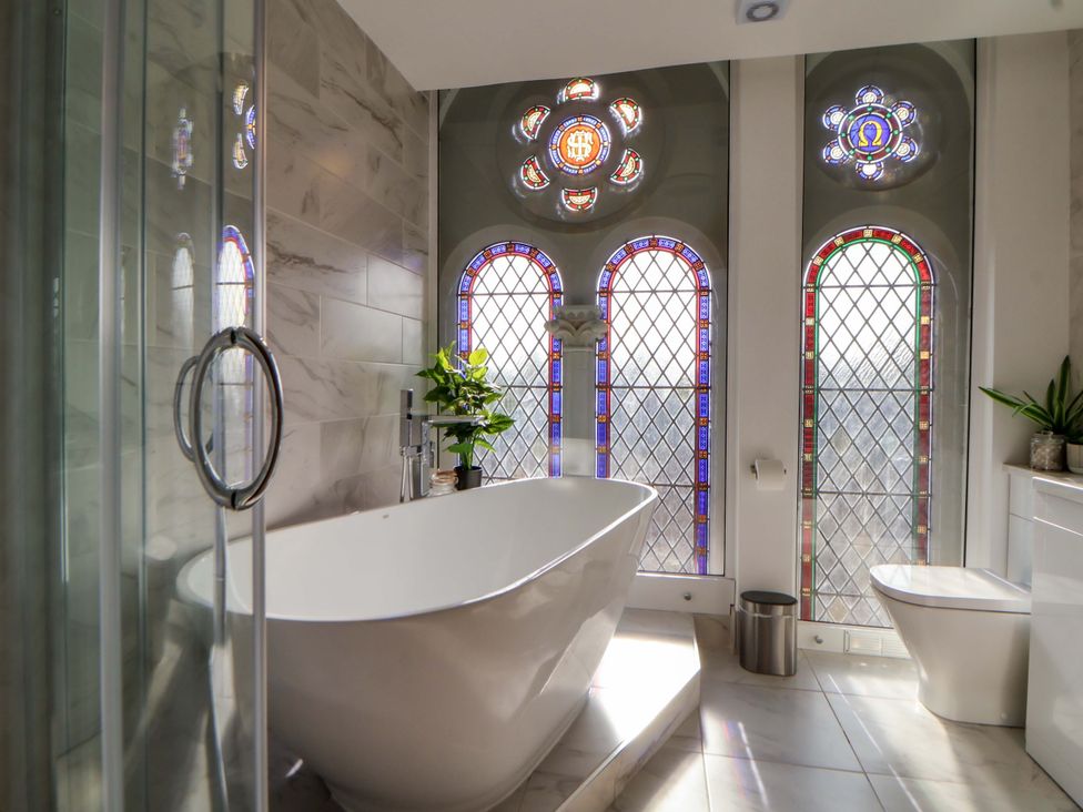 A bathroom with a bathtub and stained glass windows at 1 Chapel Place in Chester
