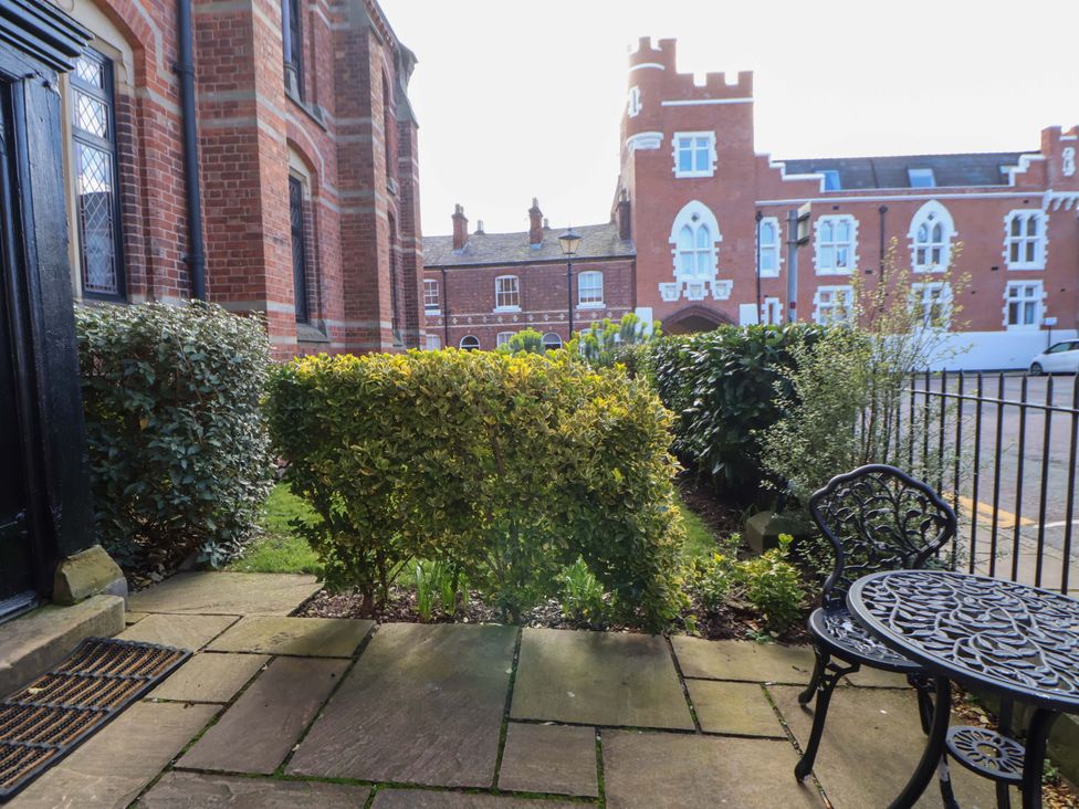 An outdoor area with a table and chair near bushes at 1 Chapel Place Chester