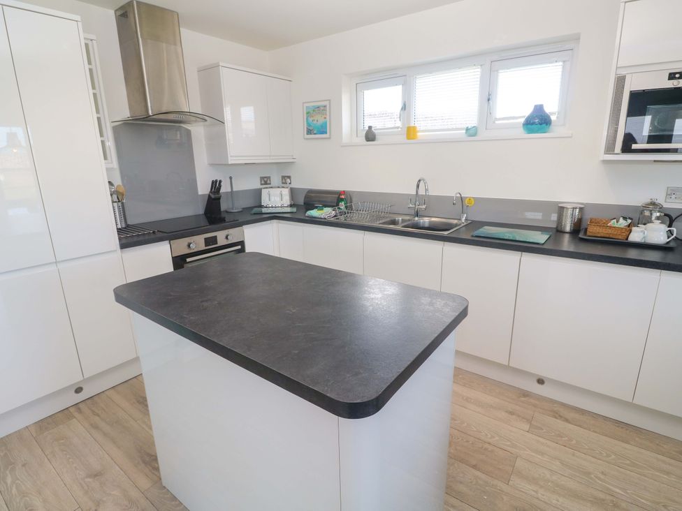 A kitchen with an island, sink, and cooking stove at Lodge 83, Gwel an Mor in Portreath