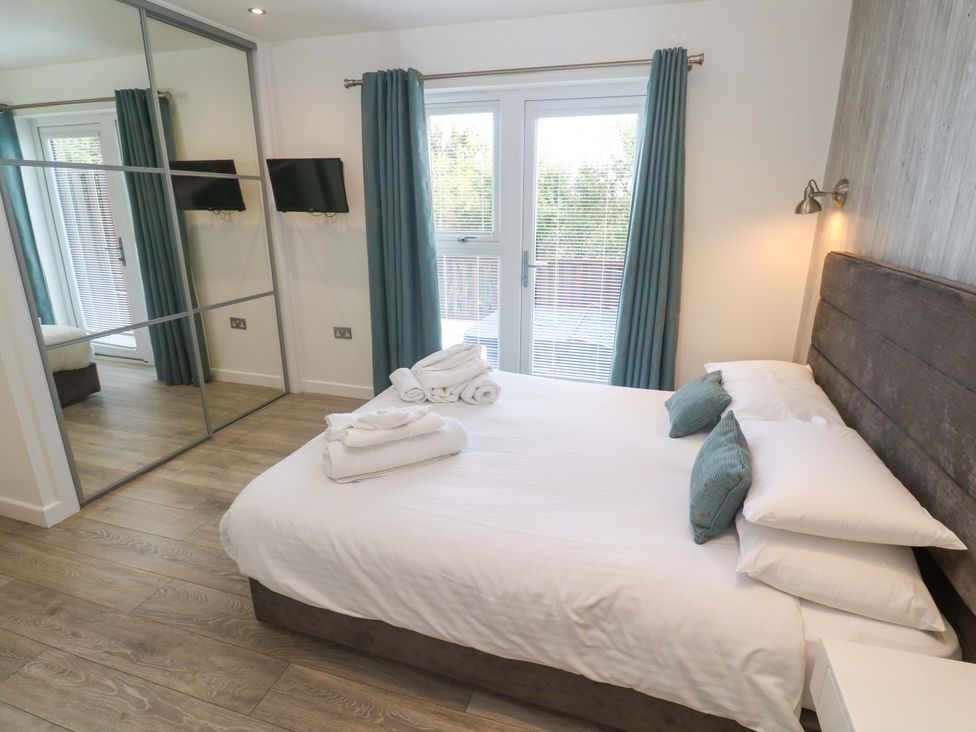 A bedroom with a bed and television at Lodge 83, Gwel an Mor in Portreath