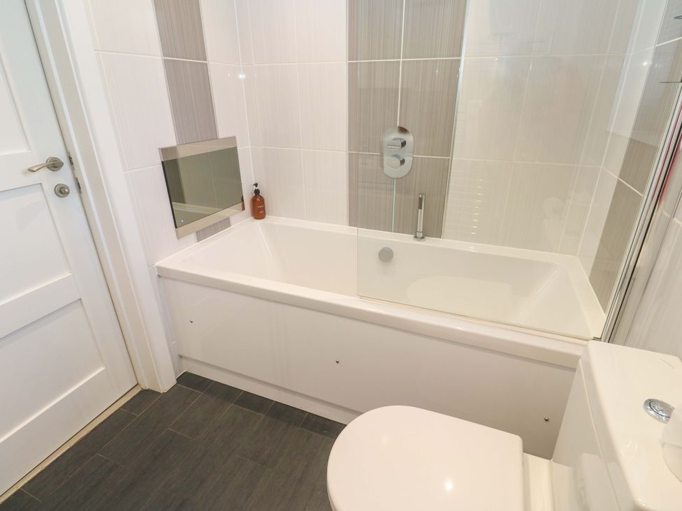 A bathroom with a bathtub and toilet at Lodge 83, Gwel an Mor in Portreath