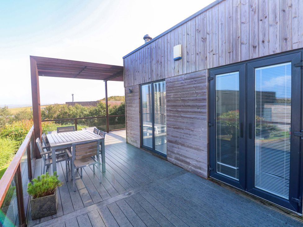 An outdoor patio with a table and chairs at Lodge 83, Gwel an Mor, Portreath