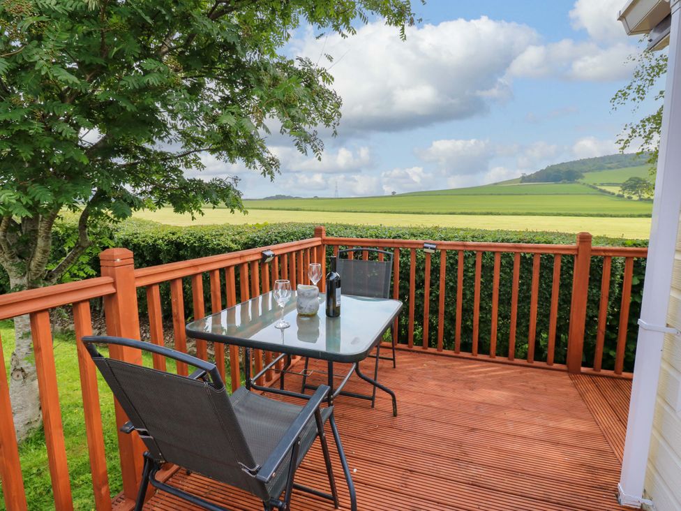 An outdoor area with a table and chairs overlooking fields at Plot 12 in Carlisle