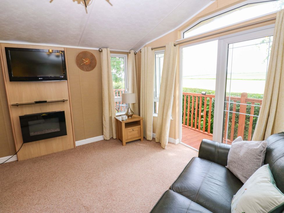 A living room with a television, fireplace, and sofa at Plot 12 in Carlisle
