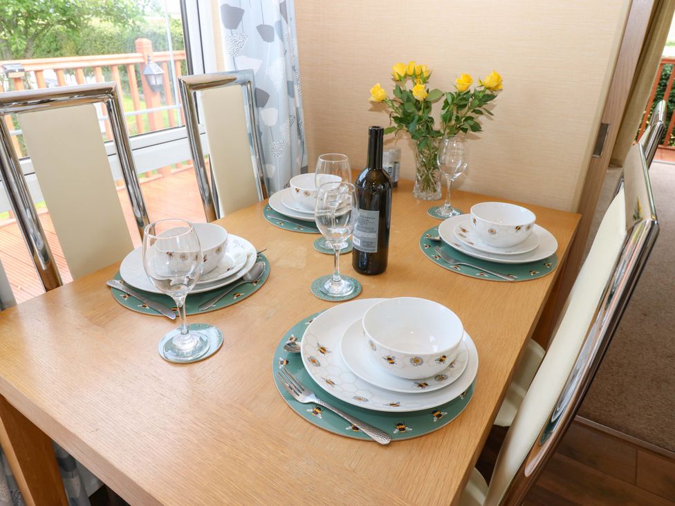 A dining table set with plates and a wine bottle at Plot 12 in Carlisle