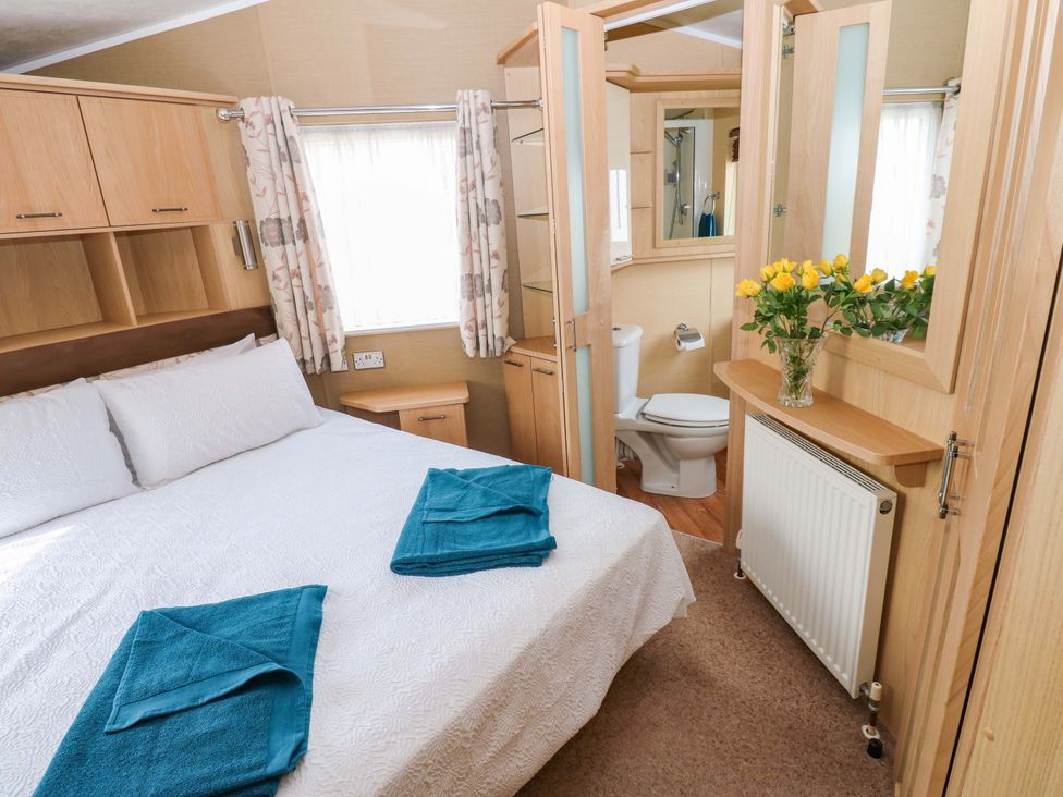 A bedroom with a bed and an adjoining bathroom at Plot 12, Carlisle