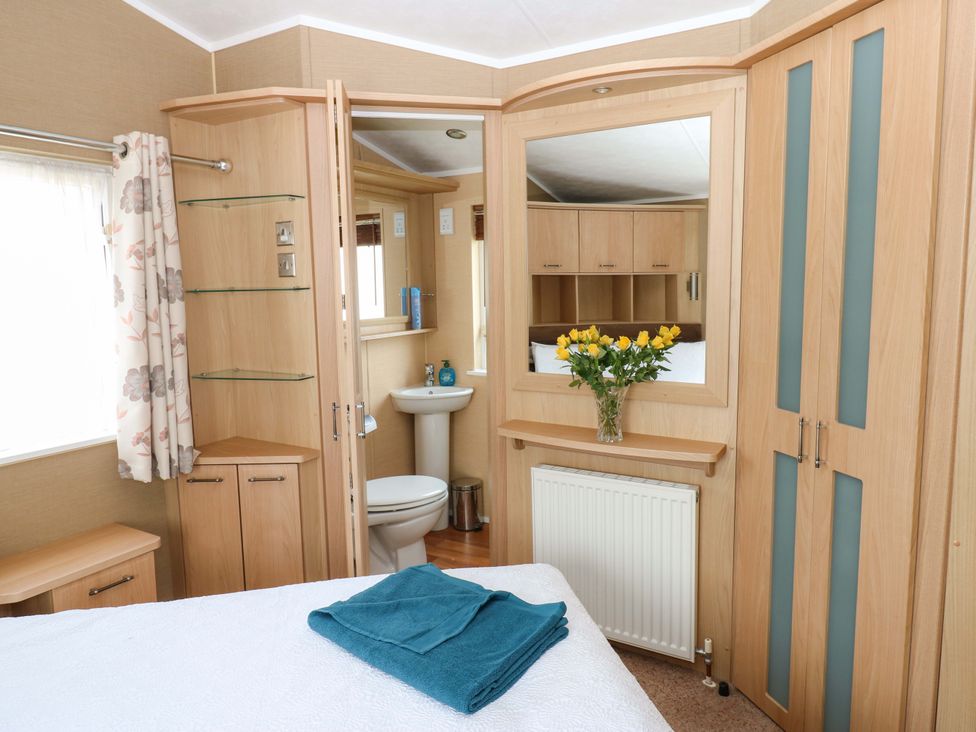 A bedroom with a bed, towel, mirror and bathroom features at Plot 12 in Carlisle