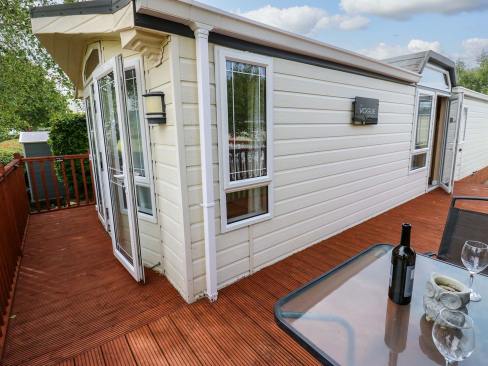 A deck area with a table and wine bottle at Plot 12 in Carlisle