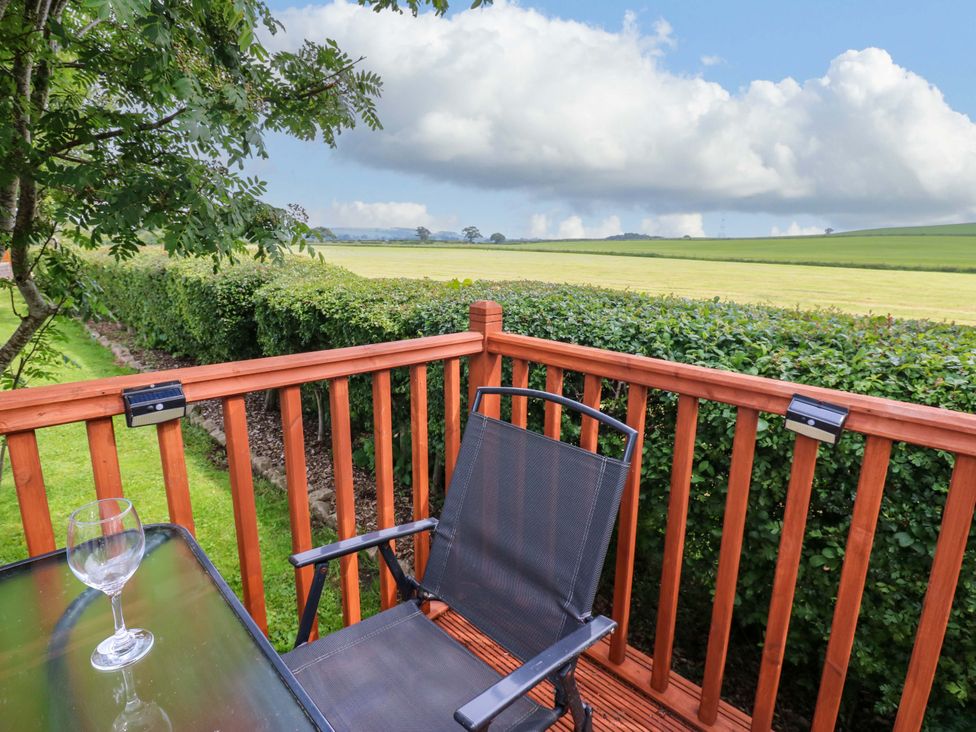 A patio with a glass and chair overlooking a field at Plot 12 in Carlisle
