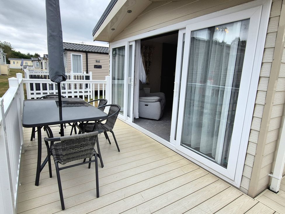 A balcony with an outdoor table and chairs at Fernwood Lodge in Fritton near Belton, Norfolk