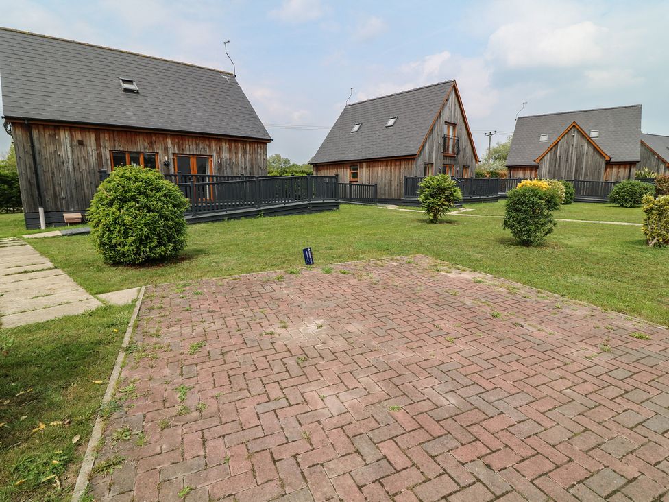 An outdoor area with wooden cabins and a paved walkway at Lodge 7 in Brigg