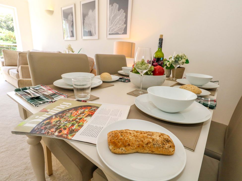 A dining table set with plates, glasses, and a fruit bowl at Apartment 11 in Poole