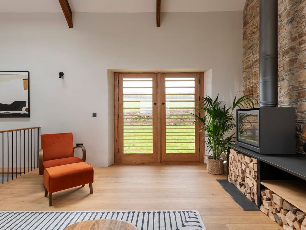 A living room with an armchair and fireplace at Lower Walreddon Farm in Tavistock