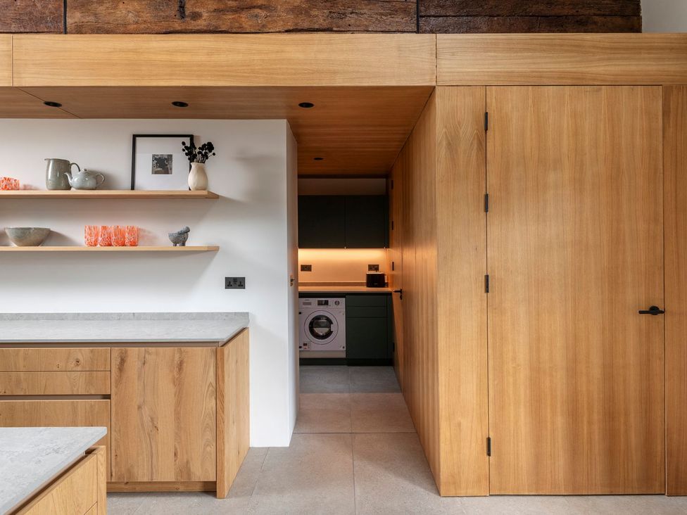 A kitchen with wooden cabinets and a washing machine at Lower Walreddon Farm in Tavistock