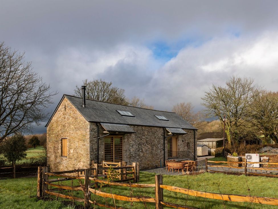 A building with a stone exterior and wooden fence at Lower Walreddon Farm in Tavistock