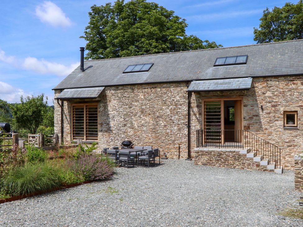 An outdoor area with a stone wall and seating at Lower Walreddon Barn Tavistock