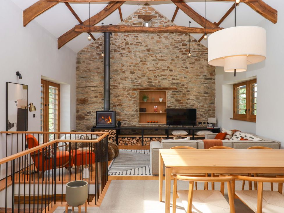 A living room with a sofa, dining table, and television at Lower Walreddon Barn in Tavistock