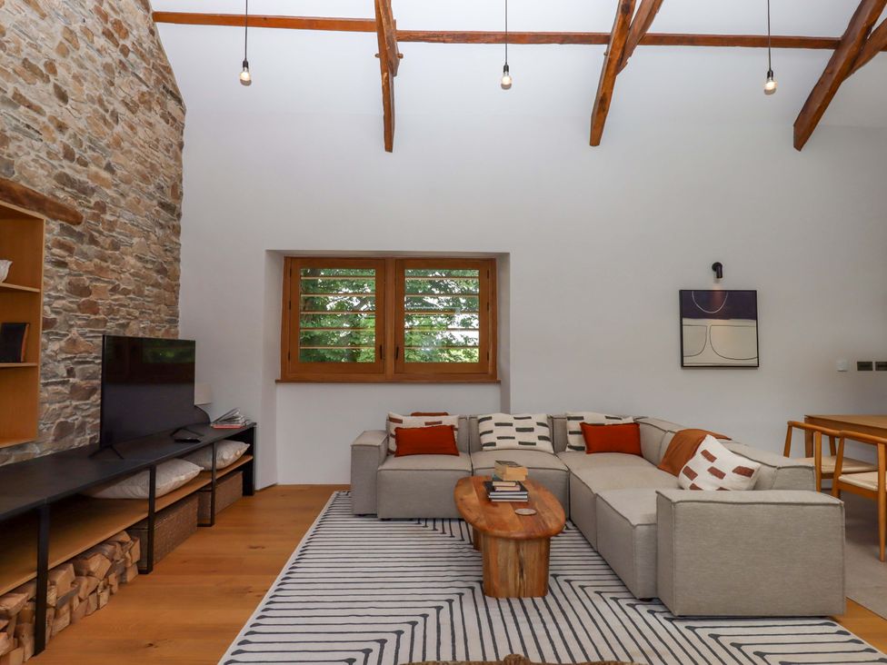 A living room with a stone wall and sofa at Lower Walreddon Barn Tavistock