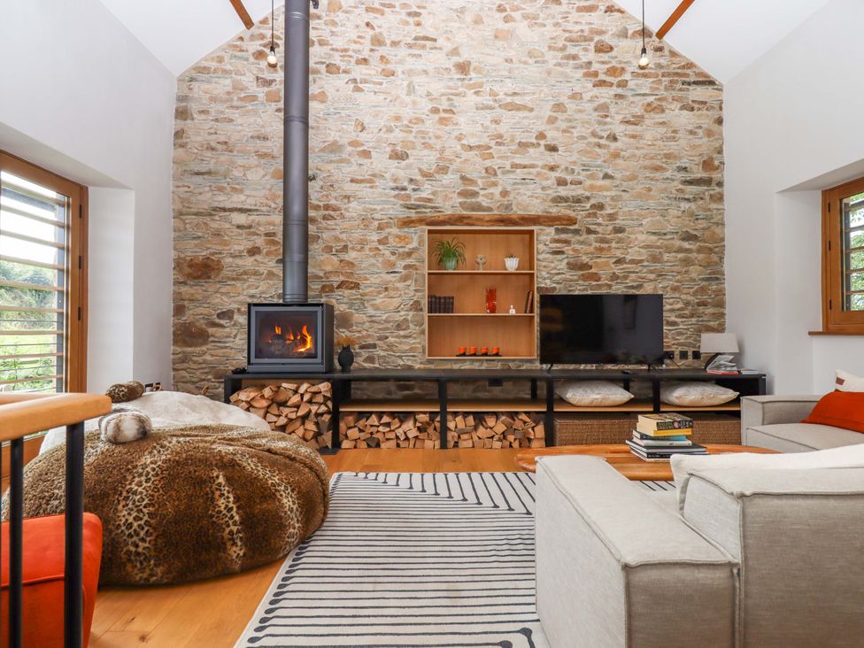 A living room with a fireplace and television at Lower Walreddon Barn Tavistock