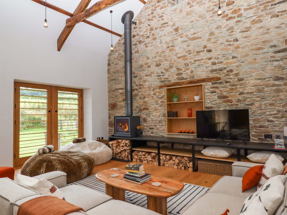 A living room with a wood stove and sofa at Lower Walreddon Barn in Tavistock