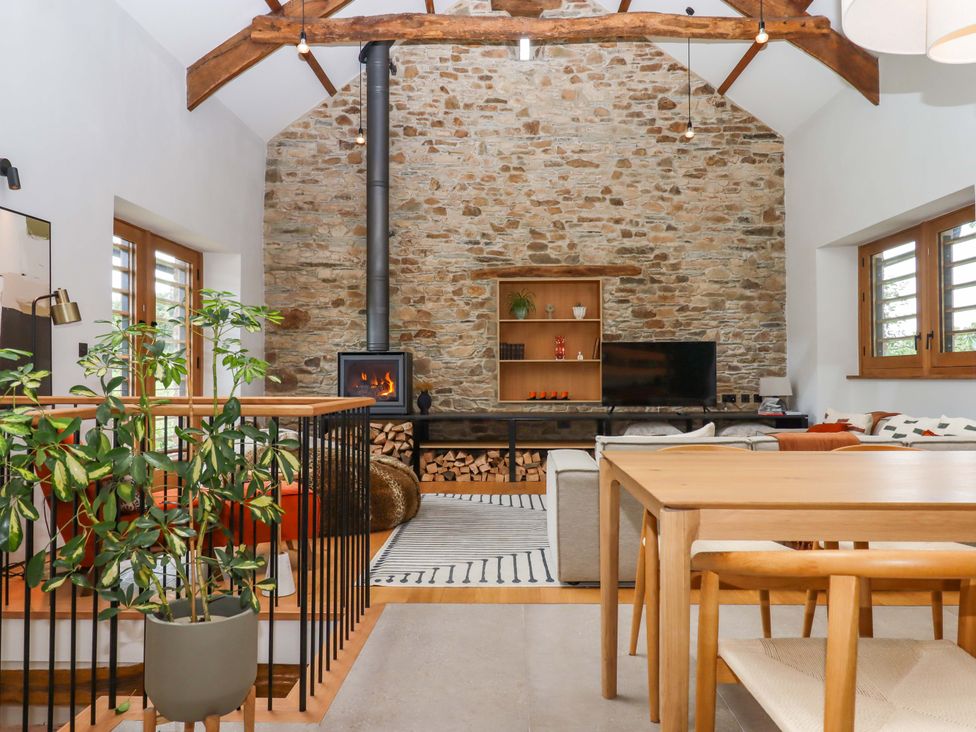 A living room with a fireplace and seating area at Lower Walreddon Barn Tavistock