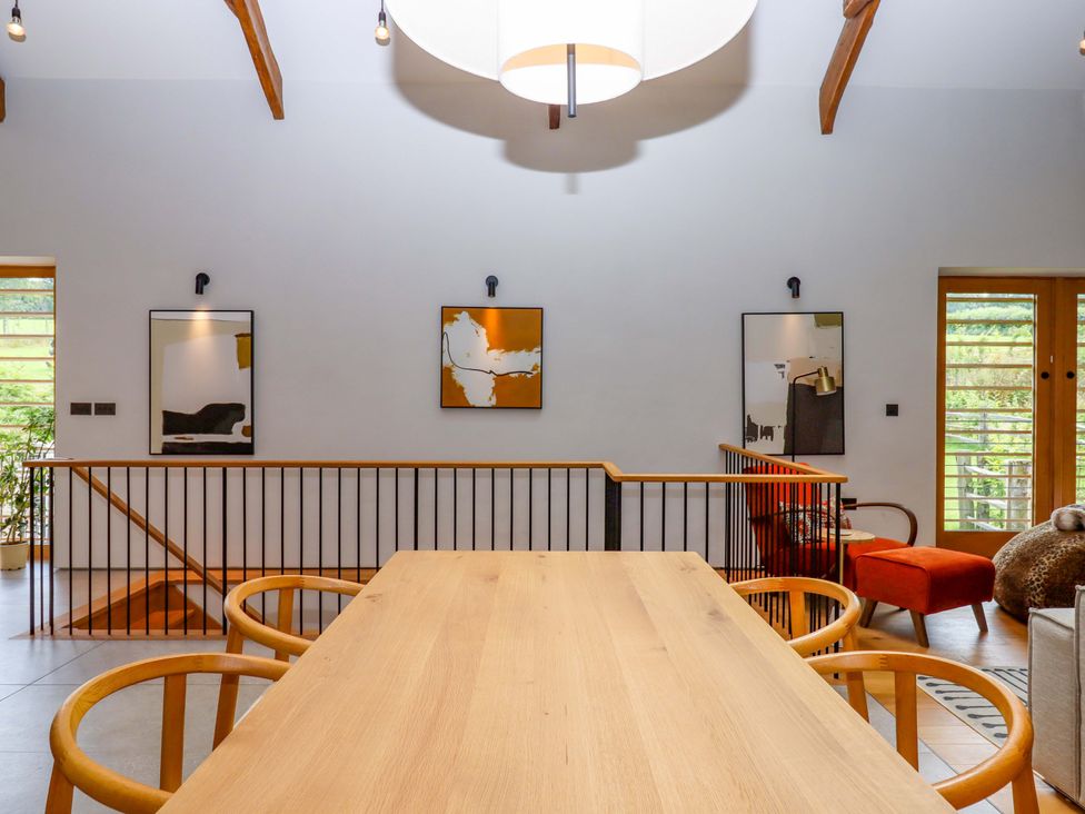 A dining room with a wooden table and chairs at Lower Walreddon Barn Tavistock