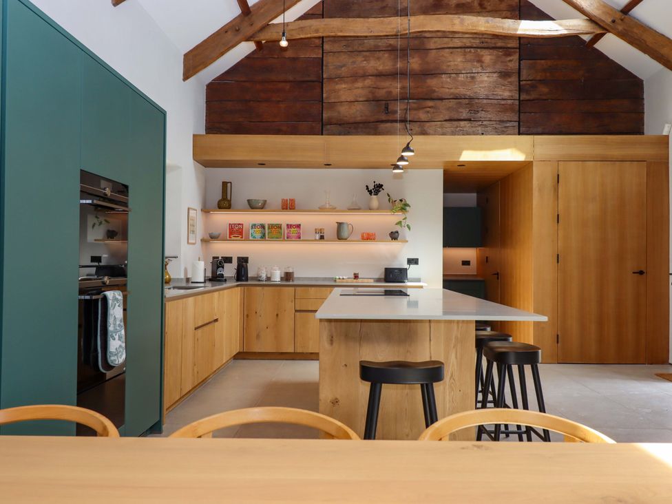 A kitchen with a central island and wooden shelves at Lower Walreddon Barn in Tavistock