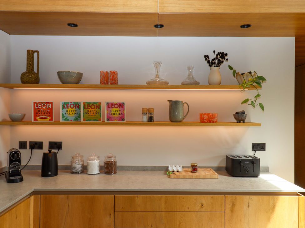 A kitchen with shelves displaying cookbooks and kitchen items at Lower Walreddon Barn Tavistock