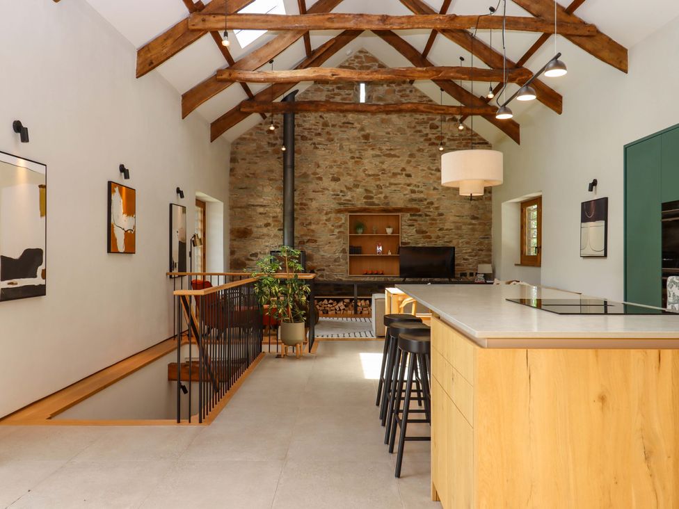 A kitchen with a large island and seating at Lower Walreddon Barn in Tavistock