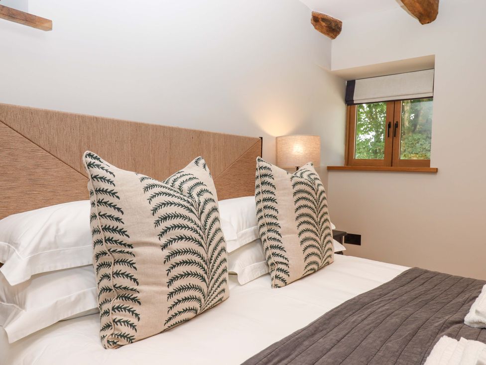 A bedroom with pillows and a window at Lower Walreddon Barn Tavistock