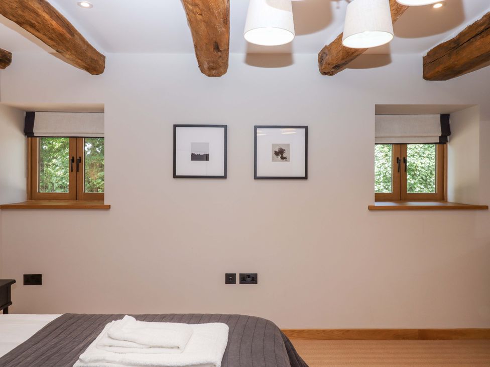 A bedroom with windows and artwork on the walls at Lower Walreddon Barn Tavistock