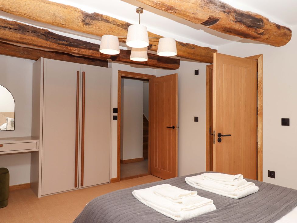 A bedroom with a bed, wardrobe, and two doors at Lower Walreddon Barn Tavistock