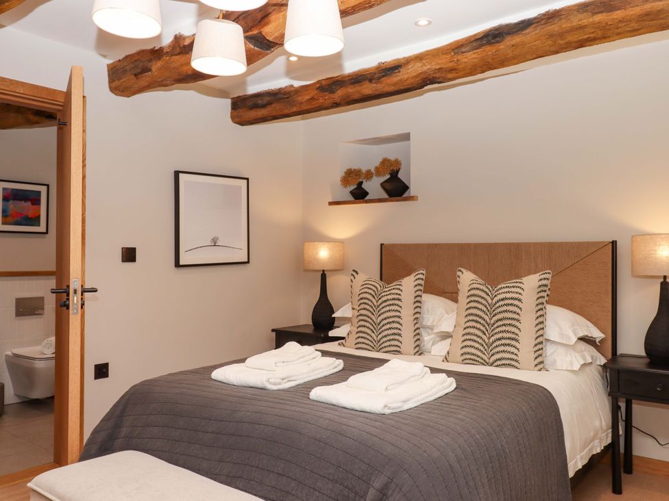 A bedroom with a bed and artwork at Lower Walreddon Barn in Tavistock