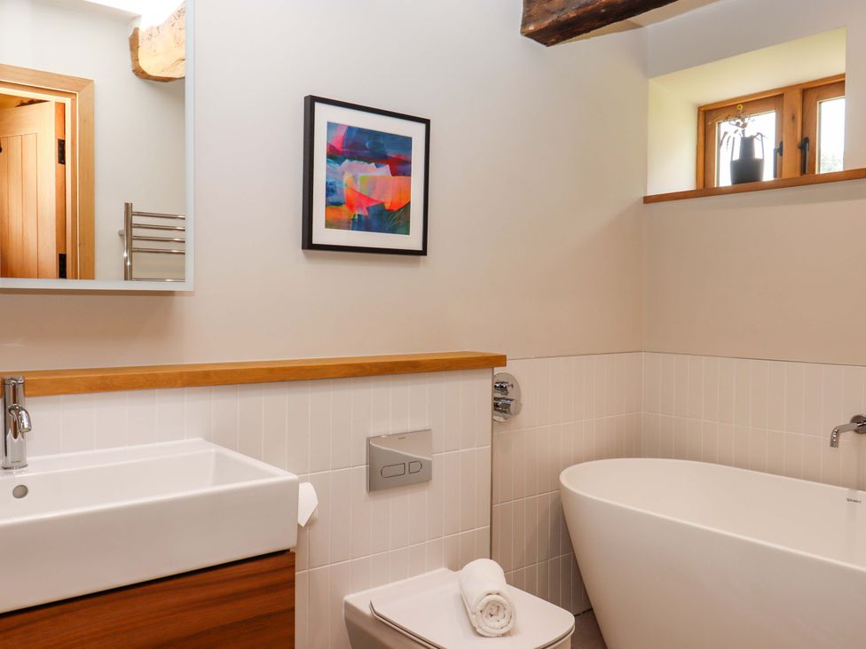 A bathroom with a sink, bathtub, and toilet at Lower Walreddon Barn in Tavistock
