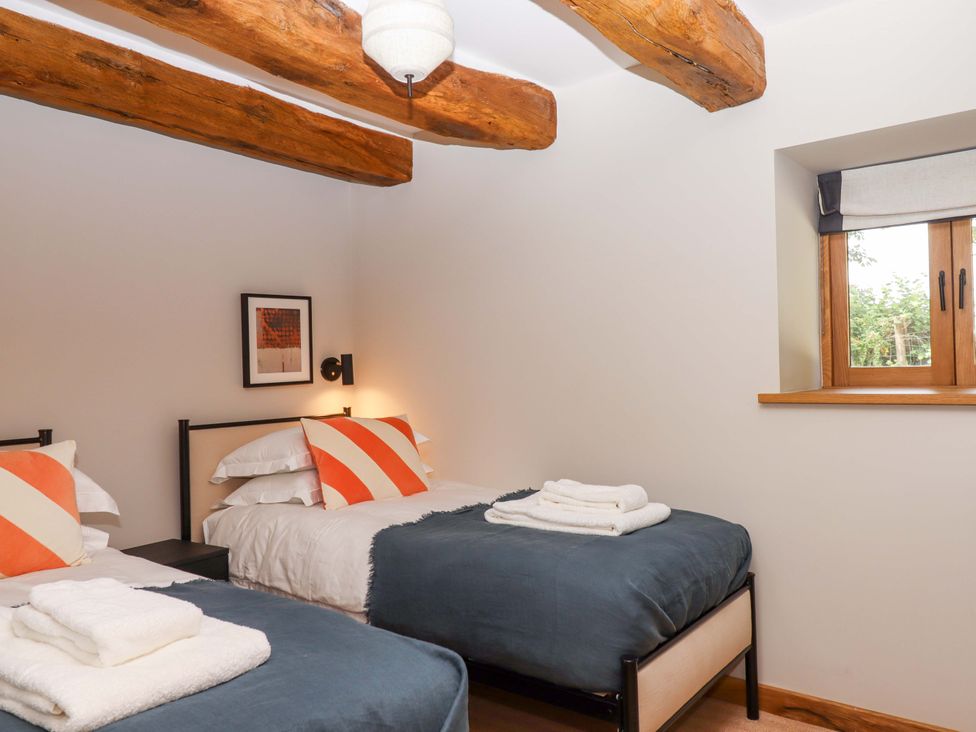 A bedroom with two beds and a window at Lower Walreddon Barn Tavistock