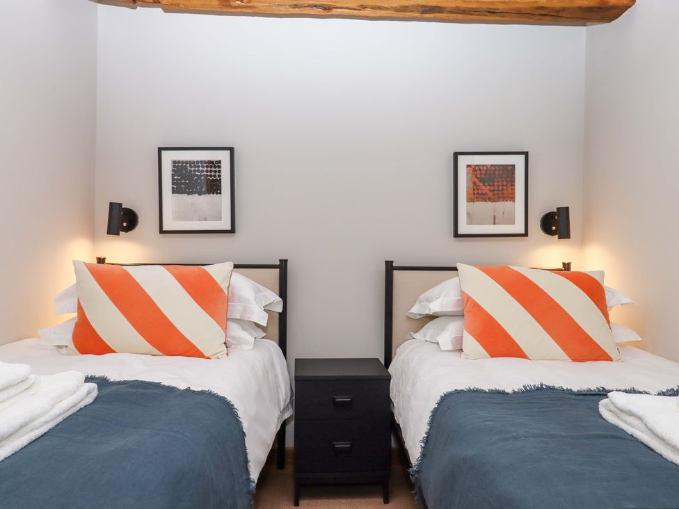 A bedroom with two beds and a nightstand at Lower Walreddon Barn in Tavistock